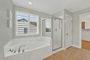Full bath featuring light tile patterned floors, a shower stall, a garden tub, and a walk in closet