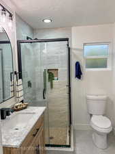 Primary Bathroom featuring a textured ceiling, a stall shower, vanity, and tile patterned floors