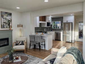 Living area with light wood-style flooring, recessed lighting, and a glass covered fireplace