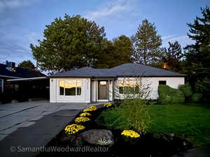 View of front of house featuring concrete driveway, a front lawn, and a shingled roof