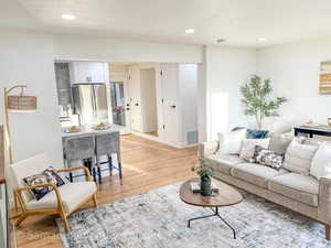 Living area with a textured ceiling, light wood-type flooring, and recessed lighting