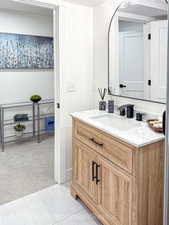 Bathroom with vanity, light colored carpet, and light tile patterned floors