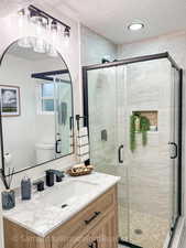 Primary Bathroom featuring a textured ceiling, vanity, and a stall shower