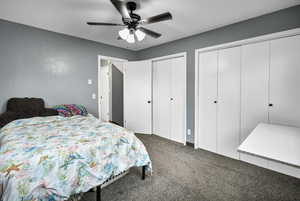 Bedroom with multiple closets, carpet floors, and ceiling fan
