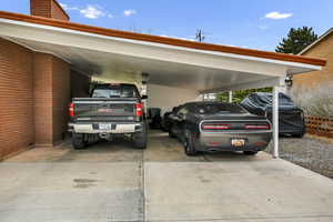 View of parking featuring an attached carport and concrete driveway
