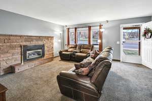 Carpeted living area with a stone fireplace