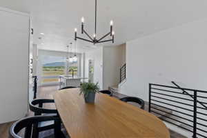 Open-concept living space featuring a modern chandelier, wood-finish flooring, and a large picture window showcasing a mountain backdrop