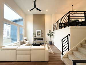 Living room with tall ceilings and an electric fireplace, open railing leading up to dining/kitchen area.
