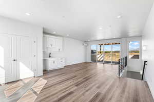 Unfurnished living room with light wood-style floors, recessed lighting, and an AC wall unit