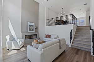 Living area with two-story ceilings, a linear electric fireplace, and wood-finish flooring