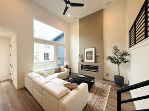 Living room with tall ceilings and an electric fireplace, open railing leading up to dining/kitchen area.