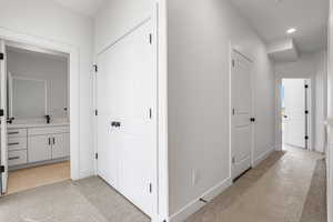 Hall with light colored carpet and recessed lighting