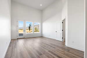 Unfurnished room featuring a towering ceiling, wood finished floors, a mountain view, and recessed lighting