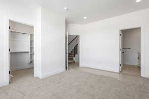 Carpeted room with white walls, featuring a walk-in closet with shelving and hanging rods