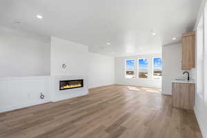 Unfurnished living room with a glass covered fireplace, light wood finished floors, and recessed lighting
