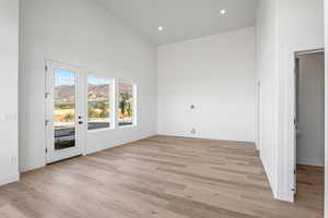 Unfurnished room with a towering ceiling, a mountain view, light wood-type flooring, and recessed lighting