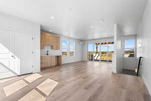 Unfurnished living room featuring light wood-type flooring, recessed lighting, and a wall unit AC