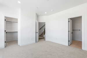 Unfurnished bedroom with a walk in closet, light carpet, and recessed lighting
