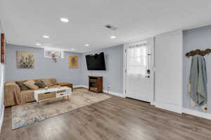 Living area with wood finished floors, recessed lighting, and a textured ceiling