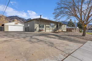 View of front facade with an outdoor structure, brick siding, a mountain view, concrete driveway, and a detached garage