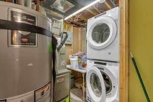 Laundry area with gas water heater and stacked washer / drying machine
