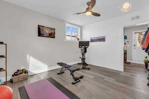 Exercise room with light wood-type flooring and a ceiling fan