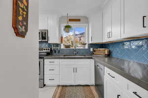 Kitchen with appliances with stainless steel finishes, backsplash, light marble finish floors, and dark countertops