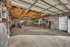 Garage with freestanding refrigerator, concrete block wall, and a garage door opener