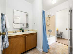 Full bathroom featuring shower / tub combo with curtain, double vanity, and light tile patterned floors