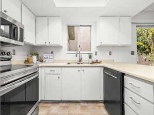 Kitchen featuring stainless steel appliances, light countertops, and white cabinetry