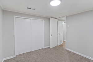 Unfurnished bedroom with carpet, crown molding, and a closet