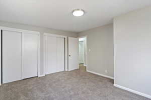 Unfurnished bedroom with multiple closets and light carpet