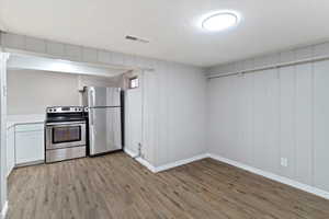 Kitchen featuring stainless steel appliances, light wood finished floors, light countertops, a textured ceiling, and white cabinets