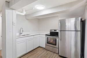 Kitchen with appliances with stainless steel finishes, light wood-style floors, and white cabinets
