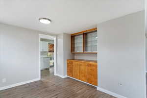 Bar area with light wood-style flooring, light countertops, and glass insert cabinets