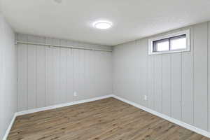 Basement with wood finished floors, wood walls, and a textured ceiling