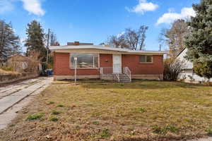 View of front of home featuring brick siding, a front yard, and driveway
