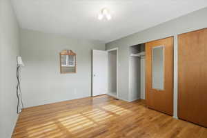Unfurnished bedroom with light wood-style floors and two closets