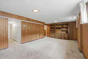 Finished basement with light carpet and wood walls
