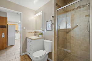 Bathroom with a shower stall, light tile patterned flooring, vanity, and tasteful backsplash