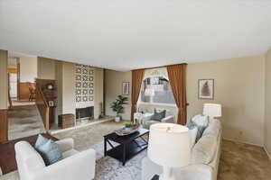 Carpeted living room featuring a fireplace and stairway