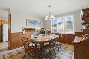 Dining room with wooden walls, a wainscoted wall, and a chandelier