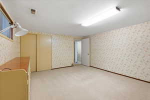 Basement featuring wallpapered walls and light colored carpet