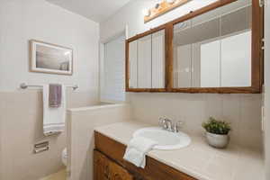 Full bathroom featuring vanity and tile walls