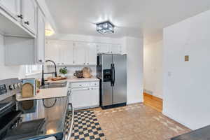 Kitchen with appliances with stainless steel finishes, light tile patterned flooring, white cabinetry, and light countertops