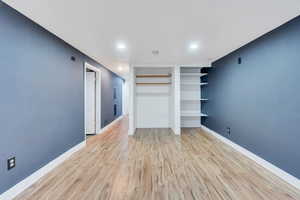 Unfurnished living room with light LVP floors, recessed lighting, and built in shelves