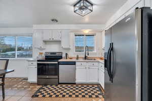 Kitchen featuring white cabinetry, appliances with stainless steel finishes, light countertops, and light tile patterned floors