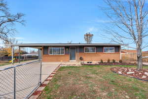 View of front facade featuring brick siding, a carport, concrete driveway, and a playground
