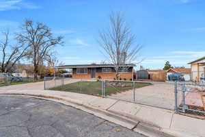View of front of home with brick siding, concrete driveway, an attached carport, and a fenced front yard