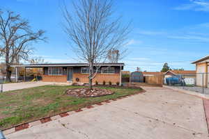 View of front of home featuring brick siding, driveway, and a carport